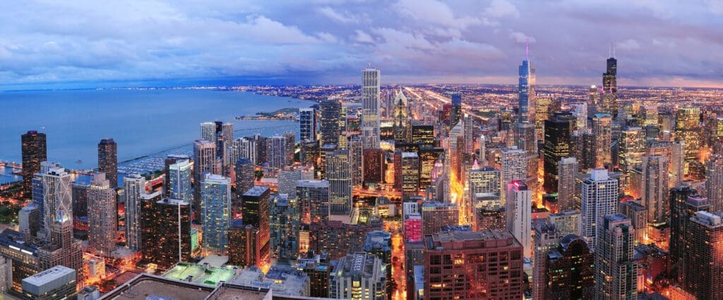 Chicago skyline panorama aerial view with skyscrapers over Lake Michigan with cloudy sky at dusk.