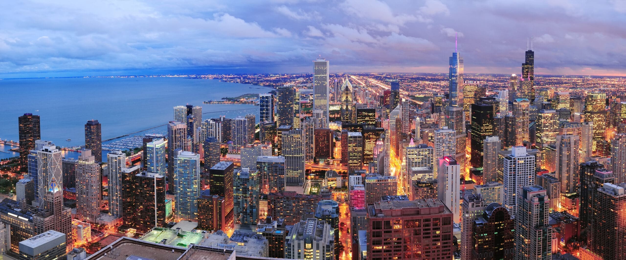 Chicago skyline panorama aerial view with skyscrapers over Lake Michigan with cloudy sky at dusk.