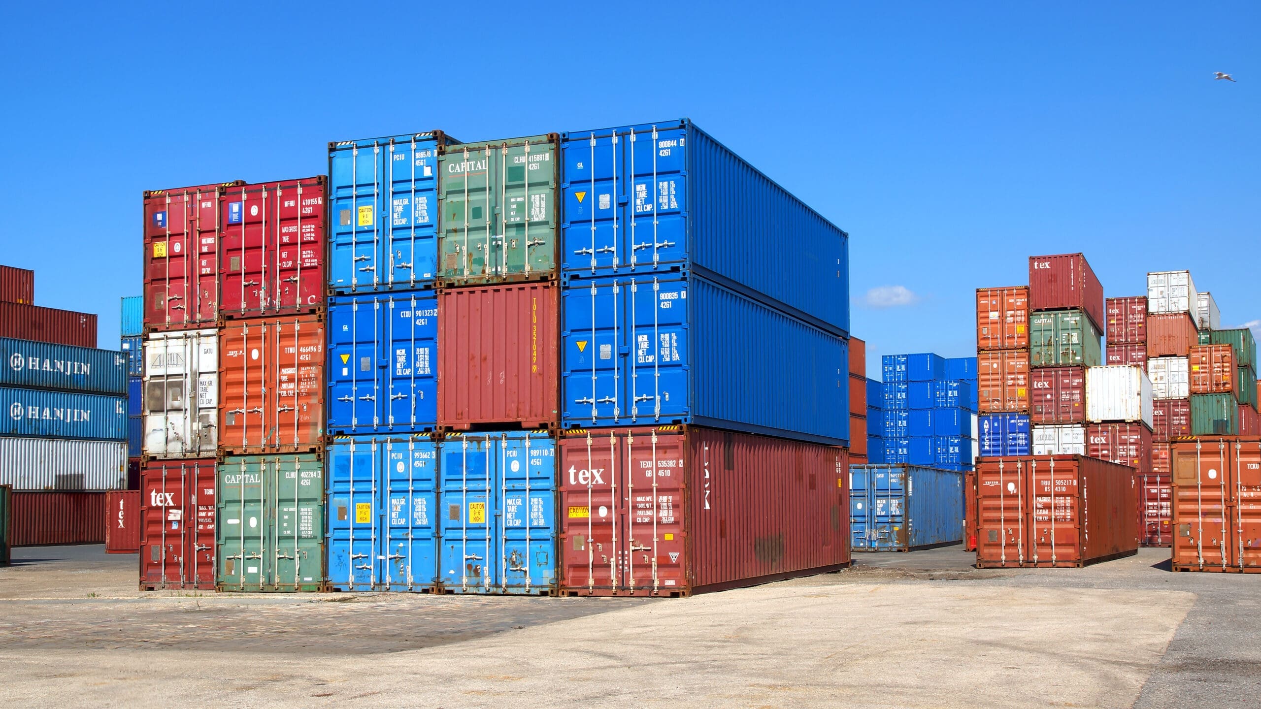 colorful shipping container new and used stacked at a depot facility